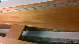 More bolts, this time inside the cabin.  The bar across the top is the staysail rail, with the toe rail bolts showing in the cubby underneath.